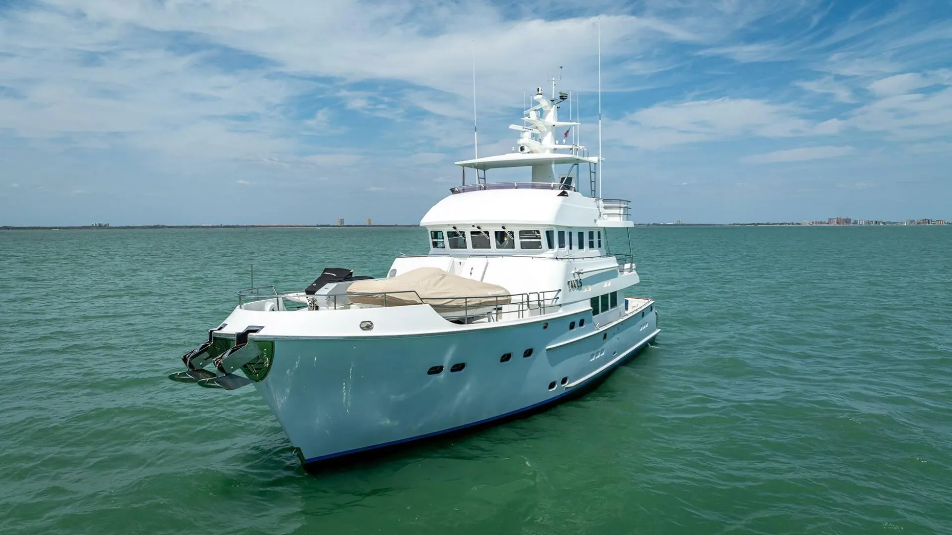 Luxurious 2009 Nordhavn 76 yacht cruising on calm waters under a clear blue sky.