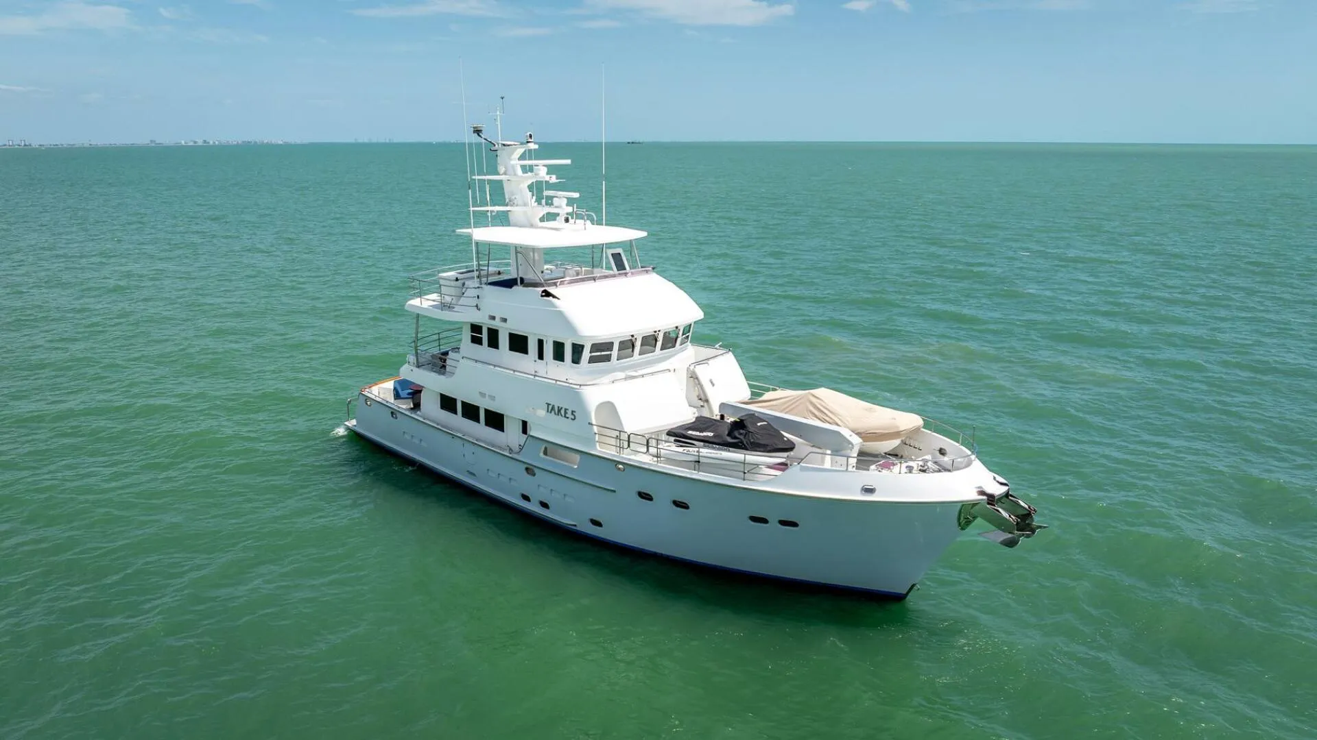 Luxurious 2009 Nordhavn 76 yacht cruising on calm, turquoise waters under a clear sky.