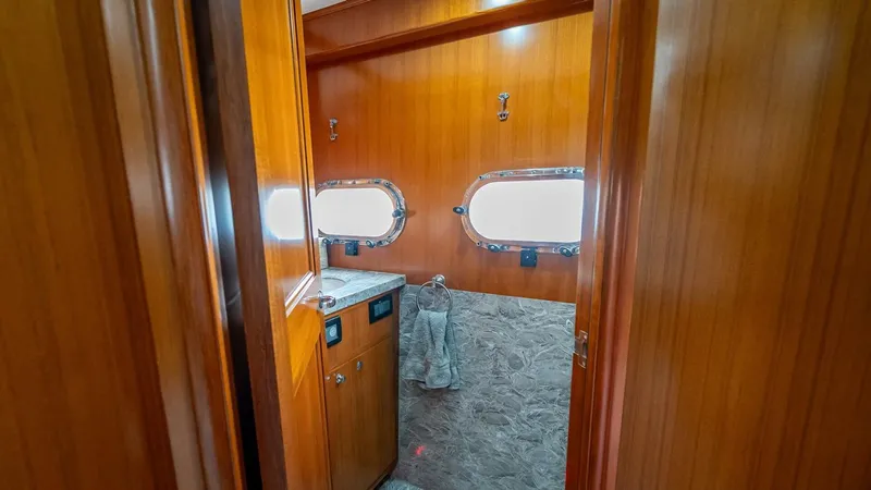 Take 5 Yacht Photos Pics Luxurious bathroom interior of 2009 Nordhavn 76 yacht with wooden finish and porthole windows.