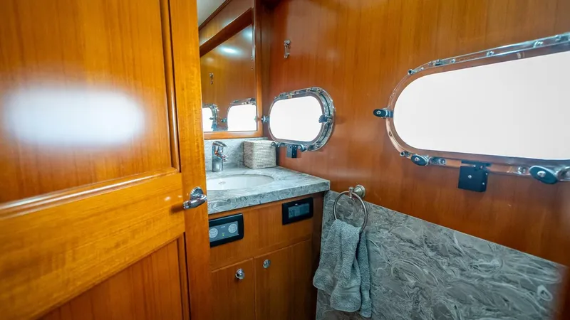 Take 5 Yacht Photos Pics Luxurious bathroom interior of 2009 Nordhavn 76 yacht with wooden cabinetry and porthole windows.