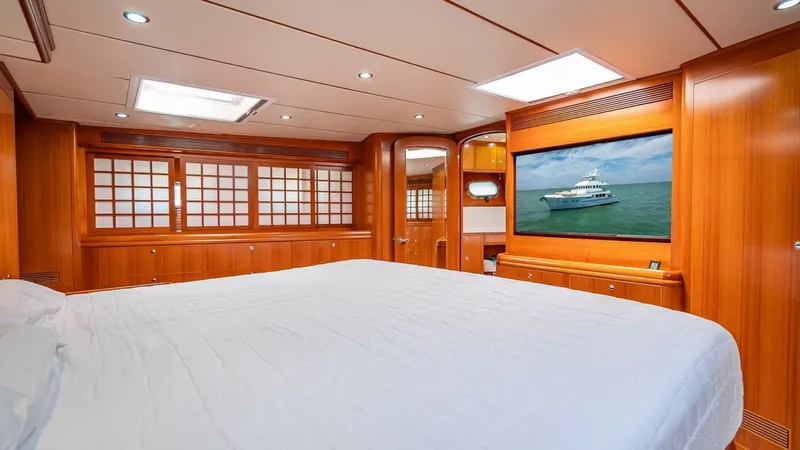 Take 5 Yacht Photos Pics Luxurious bedroom interior of 2009 Nordhavn 76 yacht with wood paneling and large TV.