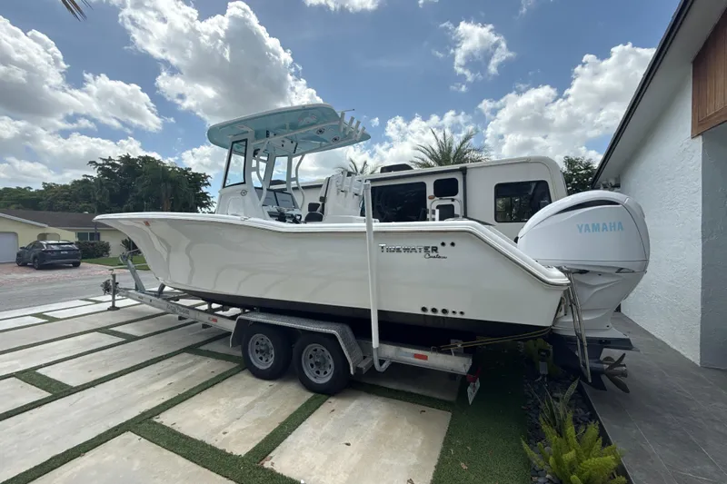  Yacht Photos Pics 2022 Tidewater 280 CC Adventure boat on trailer, parked outdoors under a cloudy sky.