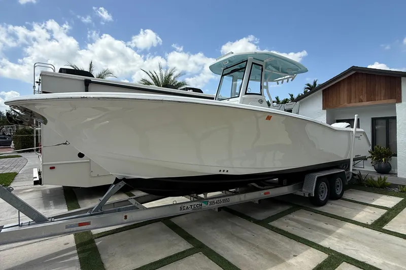  Yacht Photos Pics 2022 Tidewater 280 CC Adventure boat on trailer, parked in driveway under blue sky.