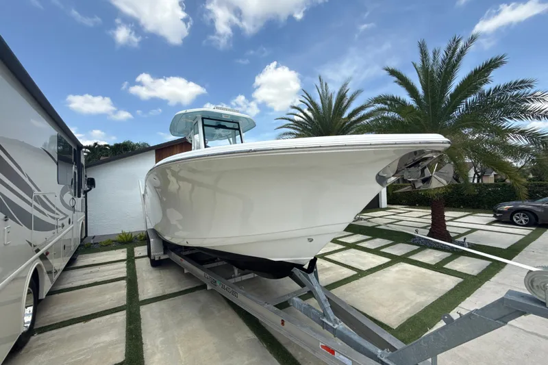  Yacht Photos Pics 2022 Tidewater 280 CC Adventure boat on trailer, parked beside RV, palm trees in background.
