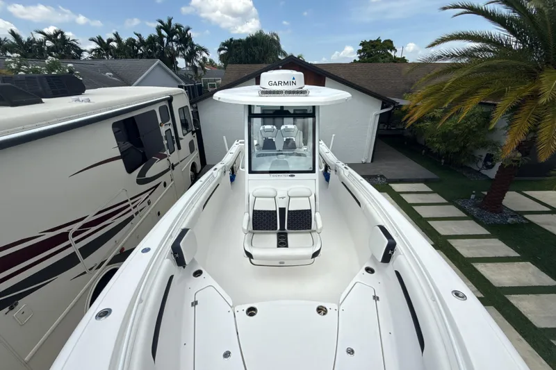  Yacht Photos Pics 2022 Tidewater 280 CC Adventure boat docked beside an RV, under a clear sky.