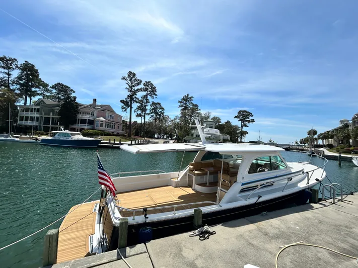  Yacht Photos Pics 2014 Back Cove Downeast 37 yacht docked by waterfront homes under clear blue sky.