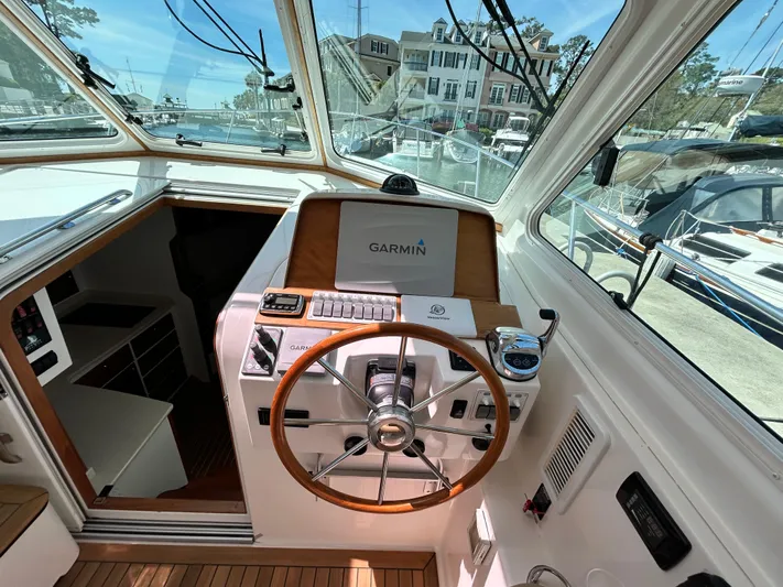  Yacht Photos Pics 2014 Back Cove Downeast 37 helm with Garmin navigation, wooden steering wheel, and marina view.