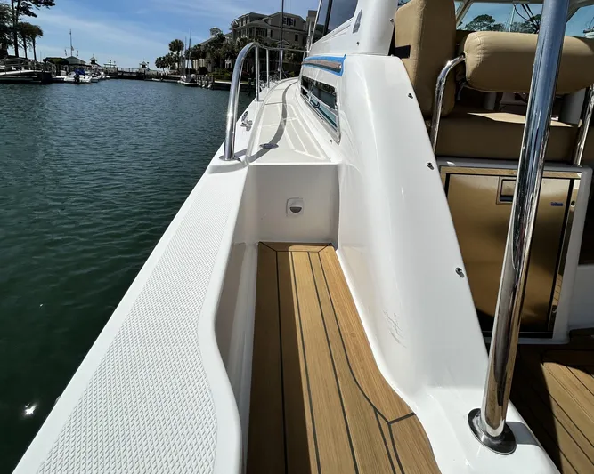  Yacht Photos Pics 2014 Back Cove Downeast 37 boat deck with teak flooring, docked by calm waters.