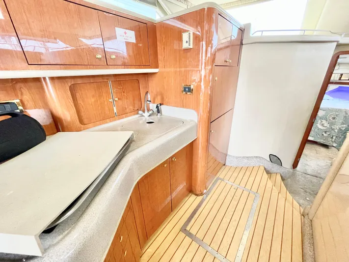  Yacht Photos Pics Interior of 2000 Sea Ray 450 Express Bridge with wooden cabinetry and compact kitchen area.