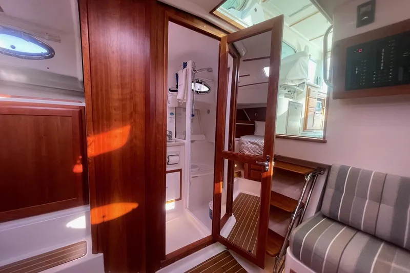 Merroir Yacht Photos Pics 2014 Back Cove 34 interior with wooden finishes, striped seating, and a cozy cabin area.