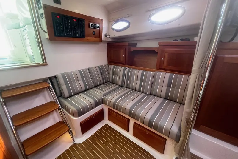 Merroir Yacht Photos Pics 2014 Back Cove 34 interior with striped seating, wooden cabinetry, and steps.