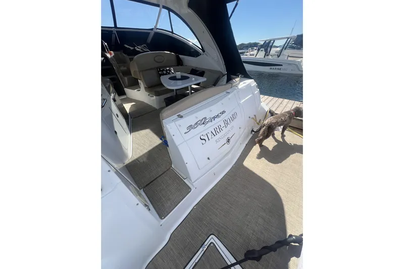  Yacht Photos Pics 2010 Cruisers Yachts 360 Express docked, interior view with seating and table, dog nearby.