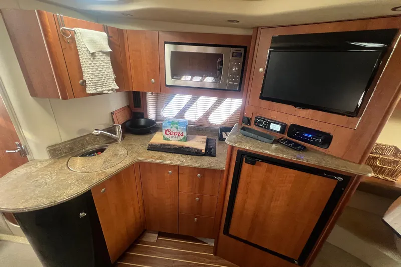  Yacht Photos Pics 2010 Cruisers Yachts 360 Express interior kitchen with microwave, TV, and wooden cabinetry.