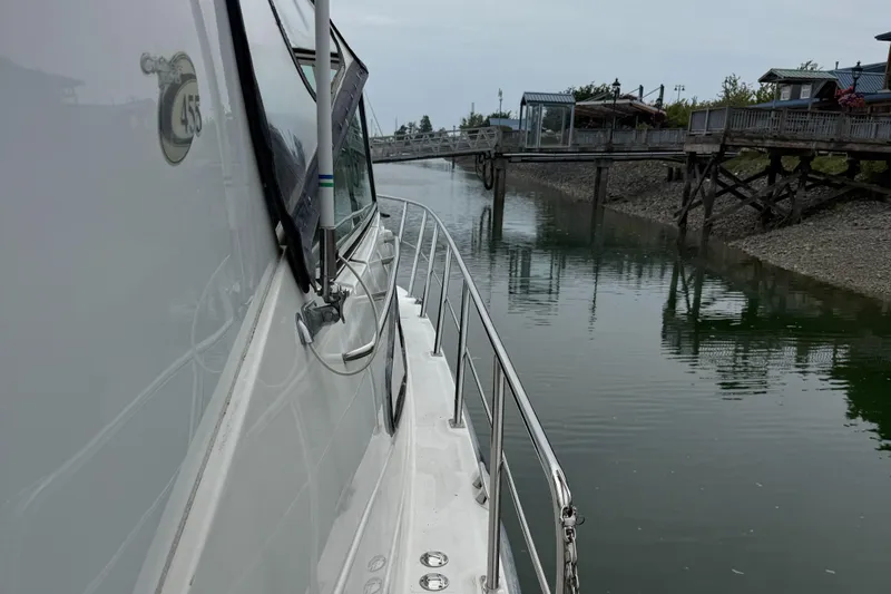  Yacht Photos Pics 2004 Cruisers Yachts 455 Express Motor Yacht docked by a calm waterfront.