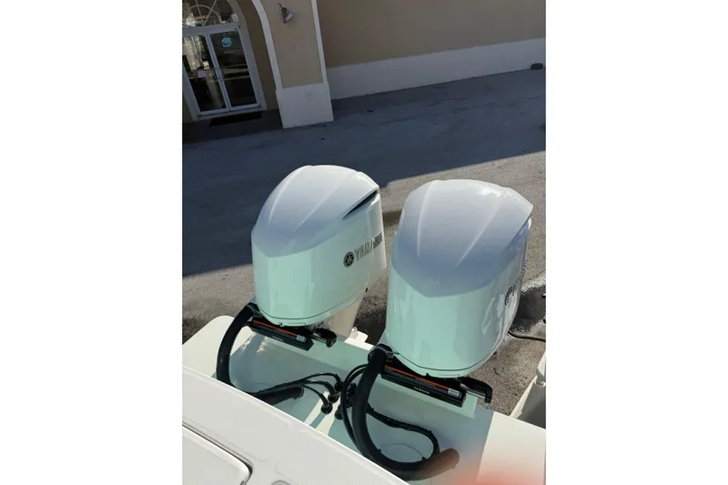 28-563 Brokerage Higgins Yacht Photos Pics Twin Yamaha outboard engines on a 2021 Regulator 28 boat, parked near a building.