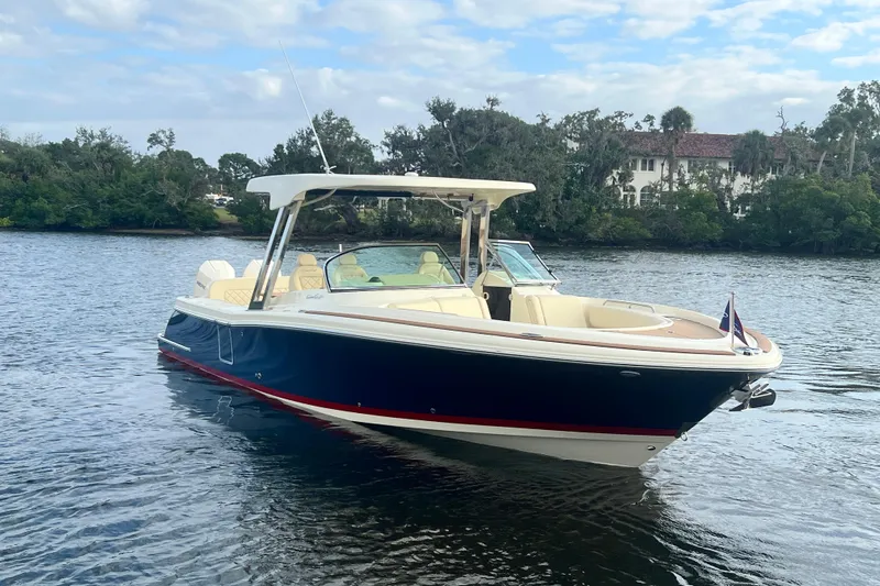  Yacht Photos Pics 2023 Chris-Craft Calypso 30 boat on calm water, surrounded by lush greenery.
