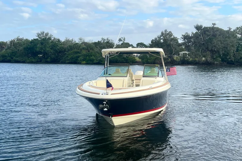  Yacht Photos Pics 2023 Chris-Craft Calypso 30 boat on calm water with trees in the background.