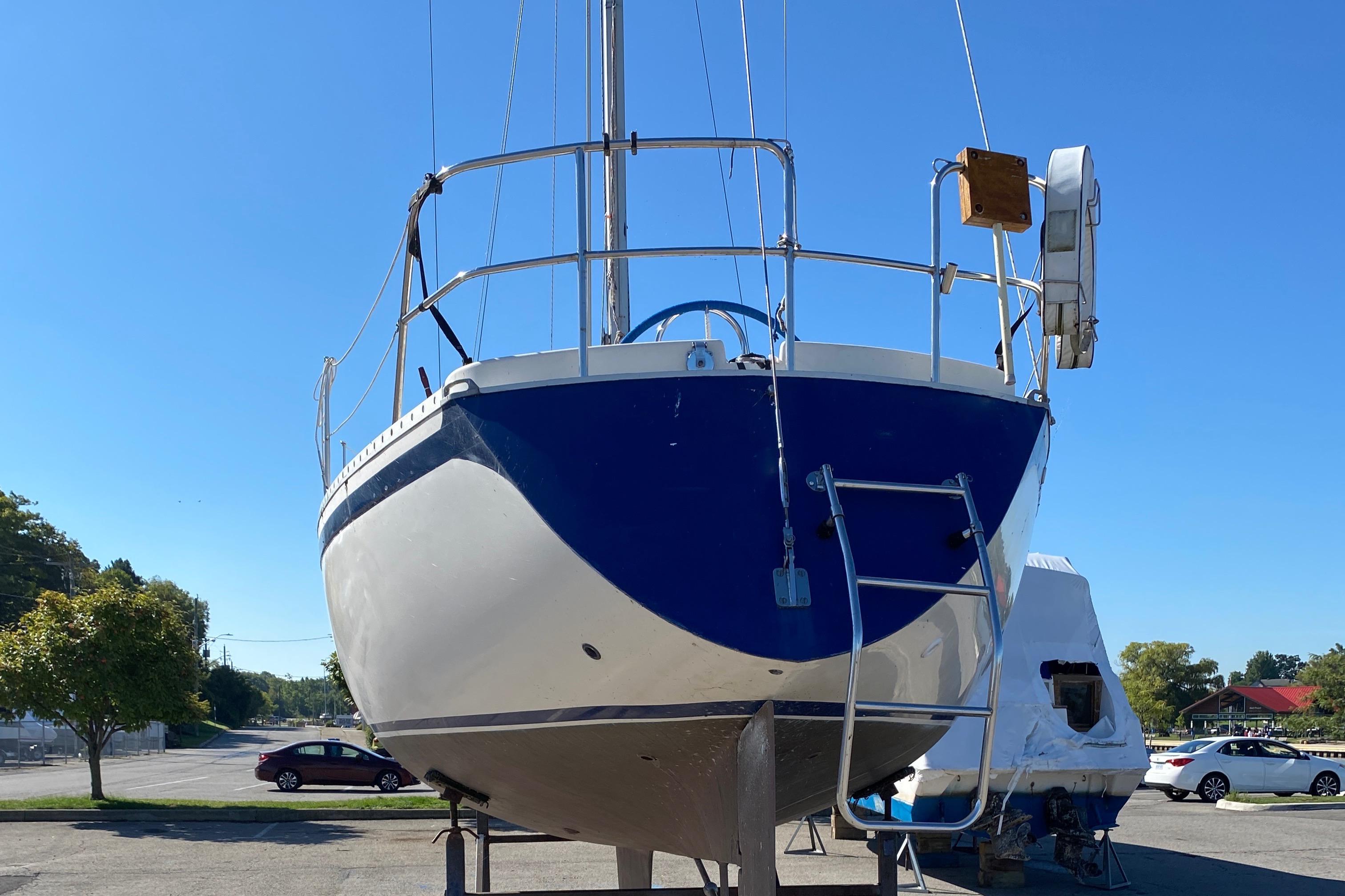 1985 CS 33 Sloop sailboat on dry dock, blue and white hull, clear sky background.