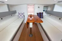 Interior of 2012 Puffin 30 Sloop with wooden table and cushioned seating.