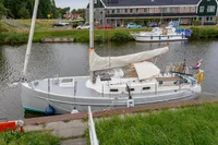Sloop sailboat Puffin 30 (9M) generation 2, 2012, docked in a scenic canal setting.