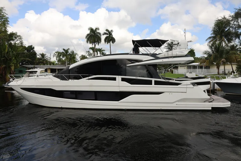  Yacht Photos Pics 2019 Galeon 650 Sky yacht docked, surrounded by palm trees and calm water.