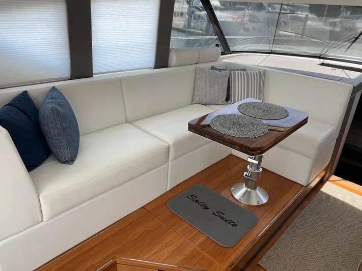 Salty Suite Yacht Photos Pics 2023 Tiara Yachts C44 Coupe interior with white seating and wooden table.