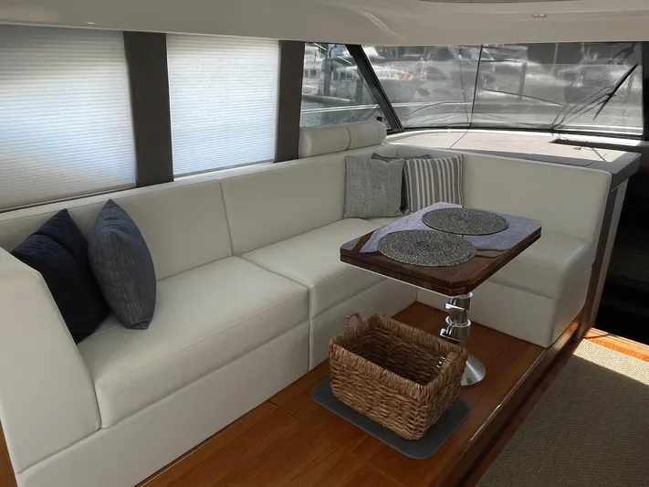 Salty Suite Yacht Photos Pics Interior of 2023 Tiara Yachts C44 Coupe with white seating and wooden table.