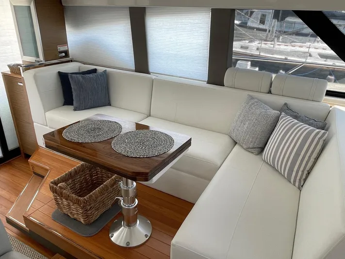 Salty Suite Yacht Photos Pics Interior of 2023 Tiara Yachts C44 Coupe with white leather seating and wooden table.