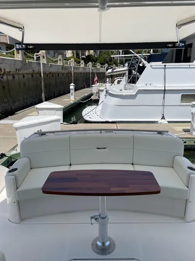 Salty Suite Yacht Photos Pics 2023 Tiara Yachts C44 Coupe, rear seating area with wooden table at marina.