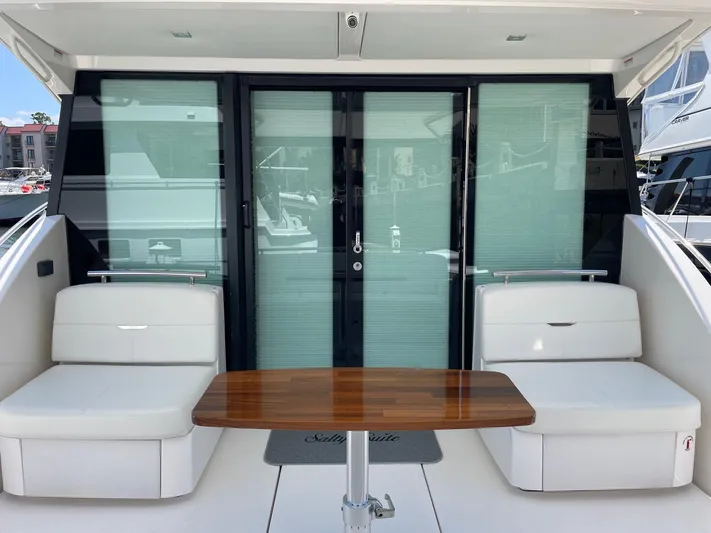 Salty Suite Yacht Photos Pics 2023 Tiara Yachts C44 Coupe cockpit with seating and wooden table.