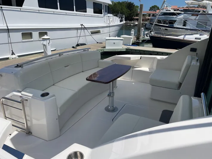 Salty Suite Yacht Photos Pics 2023 Tiara Yachts C44 Coupe, spacious cockpit with white seating and wooden table.