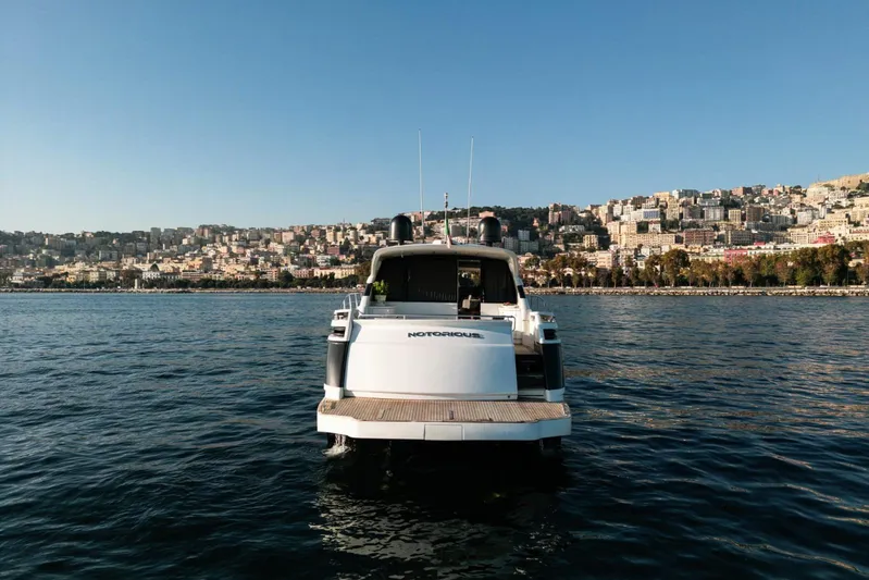 Notorious Yacht Photos Pics 2005 Pershing 62 HT yacht on water with cityscape background.