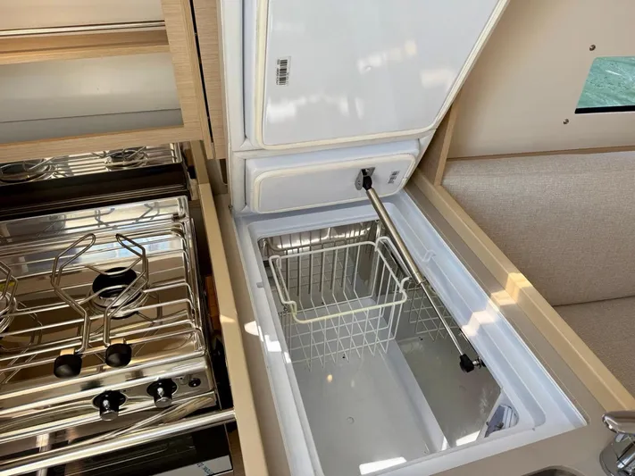 Fasttack Yacht Photos Pics Interior view of 2024 Beneteau Oceanis 30.1 yacht kitchen with stove and open fridge.