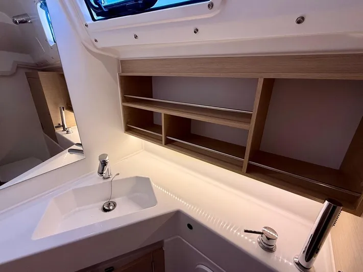 Fasttack Yacht Photos Pics 2024 Beneteau Oceanis 30.1 bathroom with modern sink, faucet, and wooden shelving.