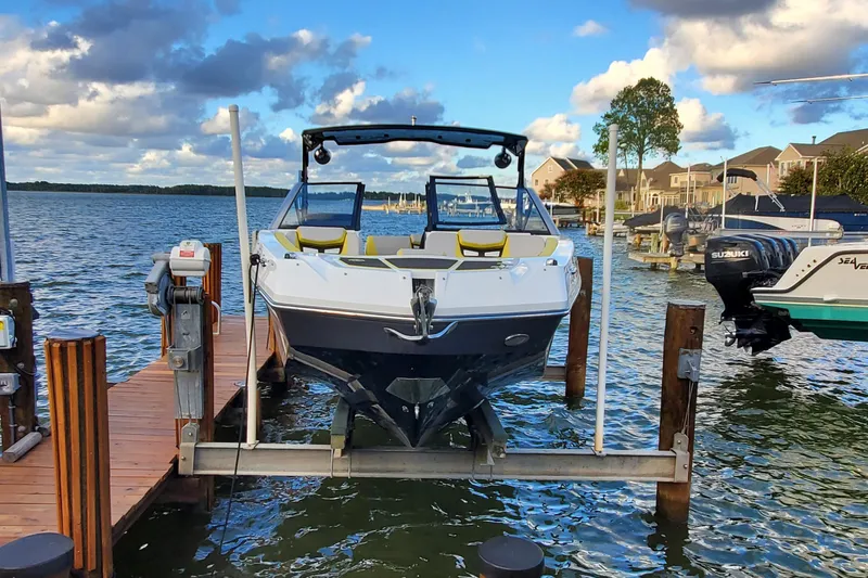  Yacht Photos Pics 2024 Scarab 285 Wake ID boat docked on a serene lake under a partly cloudy sky.