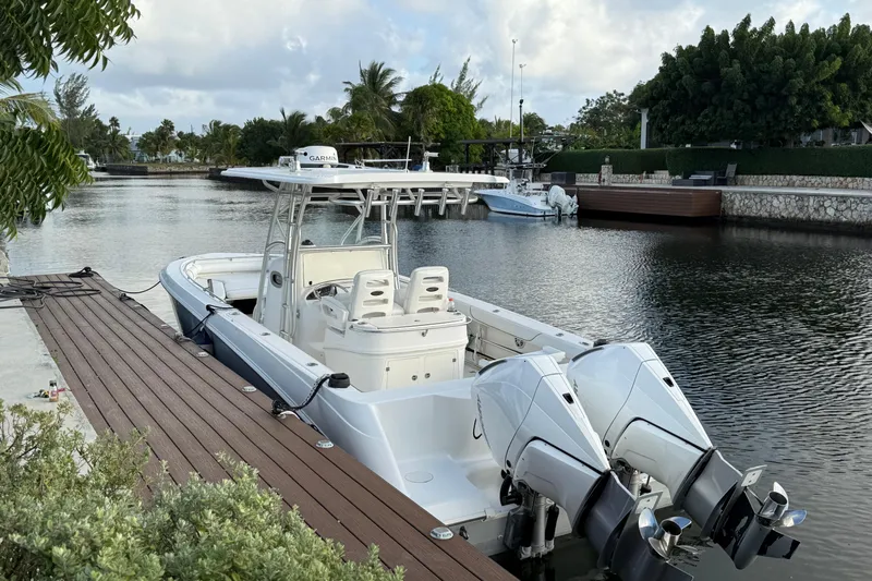 Overdraft Yacht Photos Pics 2005 Boston Whaler 320 Outrage docked by a serene waterfront with lush greenery.