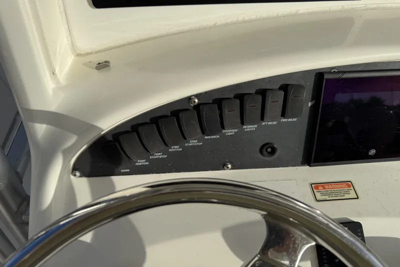 Overdraft Yacht Photos Pics Control panel of a 2005 Boston Whaler 320 Outrage boat with switches and steering wheel.