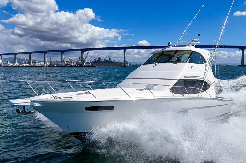 Reel Rodeo Yacht Photos Pics 2014 Maritimo 470 Offshore Convertible cruising under a blue sky near a bridge.