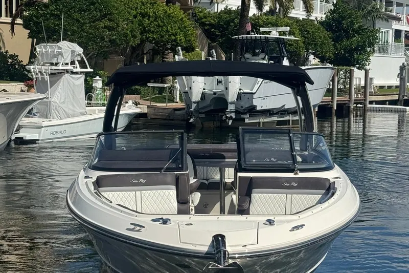  Yacht Photos Pics 2017 Sea Ray SLX 310 Outboard boat docked in a marina, surrounded by lush greenery.