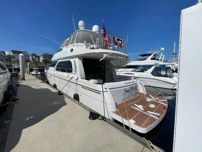 Seas The Day Yacht Photos Pics 2006 Carver 56 Voyager yacht docked at marina, featuring flags and spacious deck.
