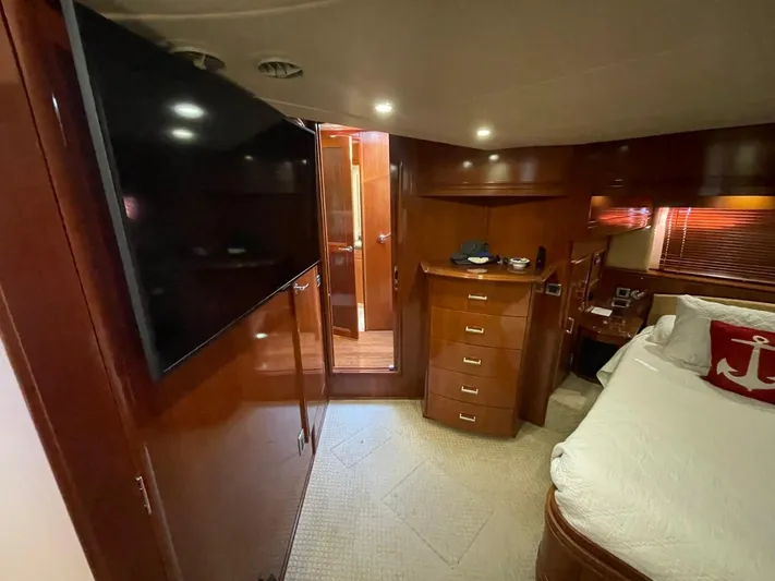 Seas The Day Yacht Photos Pics Interior of 2006 Carver 56 Voyager yacht bedroom with TV, bed, and wooden cabinetry.
