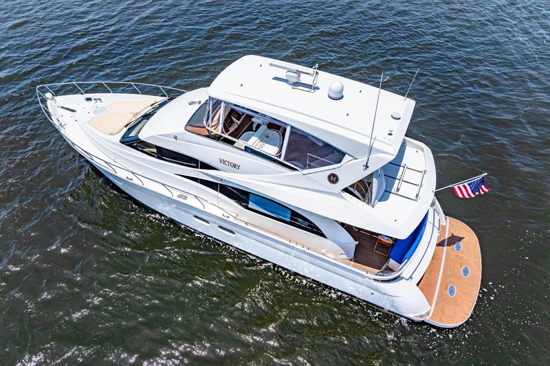 Victory Yacht Photos Pics 2005 Marquis 59 yacht cruising on open water, featuring sleek design and American flag.