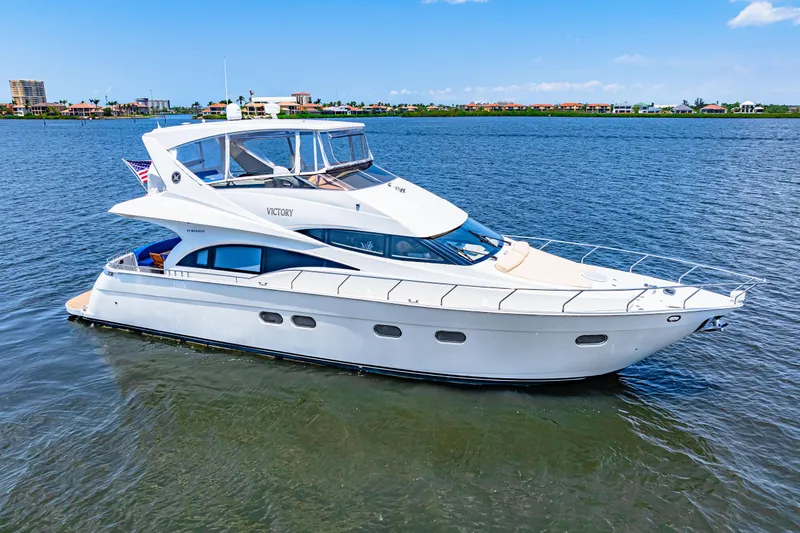 Victory Yacht Photos Pics Luxury 2005 Marquis 59 yacht cruising on a serene blue waterway.