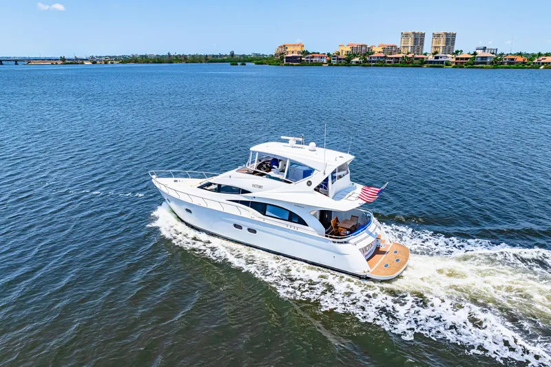 Victory Yacht Photos Pics 2005 Marquis 59 yacht cruising on a sunny day with cityscape in the background.