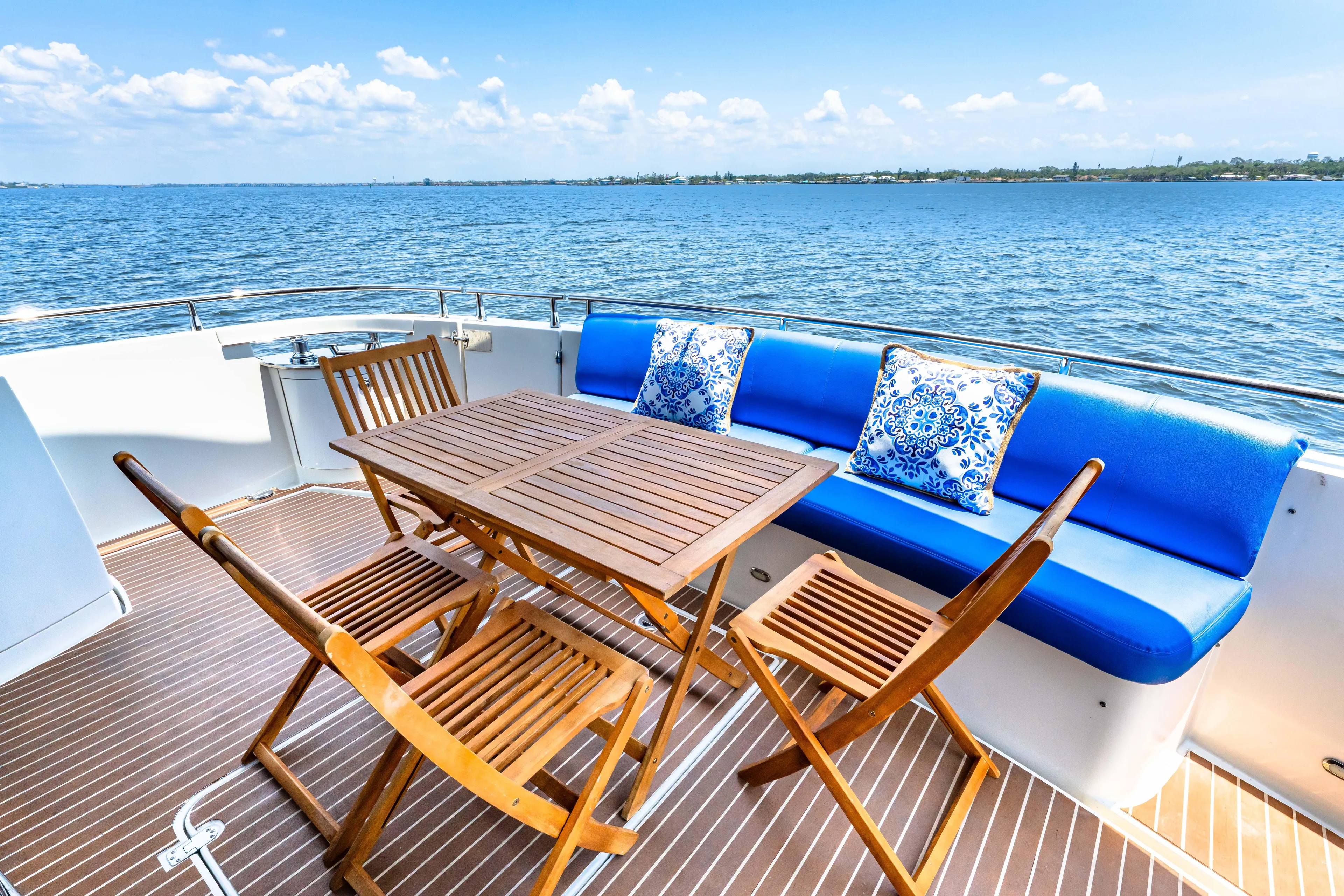 Victory Yacht Photos Pics Luxury yacht deck with wooden furniture, blue cushions, and ocean view; Marquis 59, 2005 model.