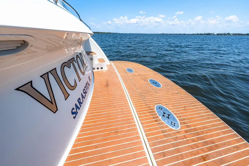 Victory Yacht Photos Pics Luxury Marquis 59 yacht on open water, featuring teak deck and clear blue sky.