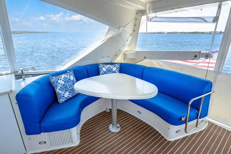 Victory Yacht Photos Pics 2005 Marquis 59 yacht interior with blue seating, white table, and ocean view.