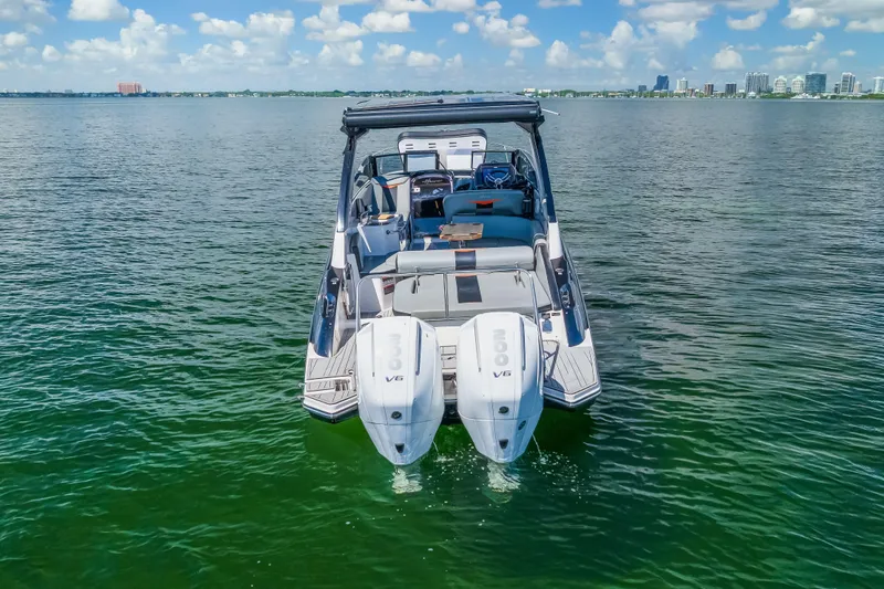  Yacht Photos Pics 2025 Hanover 305 boat with dual engines on calm water, city skyline in background.