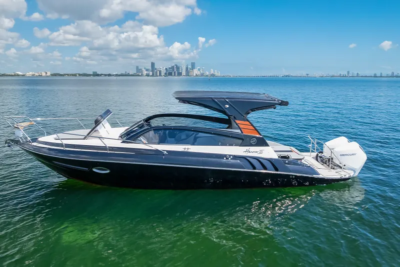  Yacht Photos Pics 2025 Hanover 305 boat on calm water with city skyline in background.