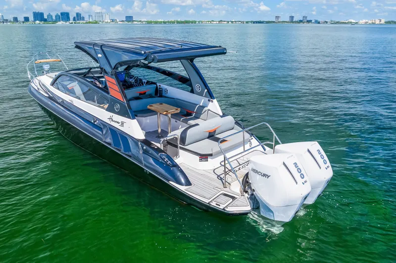  Yacht Photos Pics 2025 Hanover 305 boat on water with twin Mercury engines, city skyline in background.
